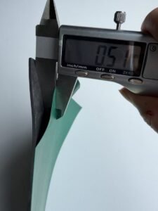 Digital caliper measuring the green dissipative top layer of a 2 mm ESD bench mat at 0.51 mm, measured at the cut cross-section