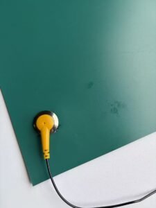 Ground snap installed through the green dissipative surface of an ESD bench mat