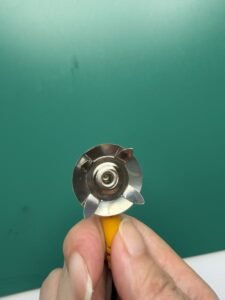 Underside of an ESD mat ground snap showing the four metal prongs that pierce the mat to contact the conductive layer