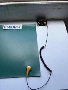 ESD bench mat connected by ground cord to a common point ground with a wrist strap coil cord attached